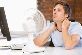 Businessman using electric fan at computer